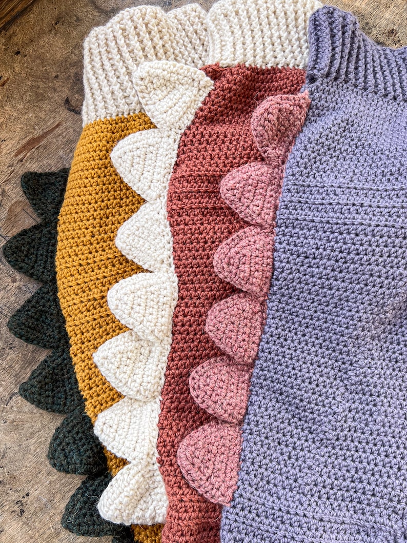 May include: A collection of four crocheted garments featuring ribbed necklines and rows of triangular spikes along the side. The items are colored in dark green, mustard yellow, cream, terracotta, and lavender, each with matching spikes.