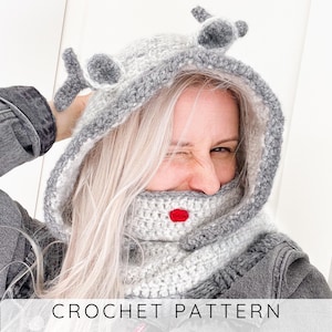 May include: A gray and white crocheted hood with attached ears and a red mouth detail. The hood is part of a crochet pattern. The text "CROCHET PATTERN" is displayed at the bottom of the image.