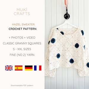 Op de afbeelding: Cr&egrave;mekleurige gehaakte trui met donkerblauwe bloemaccenten, hangend aan een witte hanger. De trui is gemaakt van granny squares. De tekst op de afbeelding luidt "HAZEL SWEATER CROCHET PATTERN".