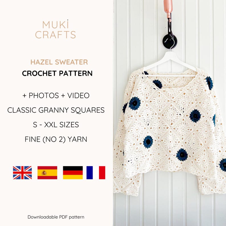 Op de afbeelding: Cr&egrave;mekleurige gehaakte trui met donkerblauwe bloemaccenten, hangend aan een witte hanger. De trui is gemaakt van granny squares. De tekst op de afbeelding luidt "HAZEL SWEATER CROCHET PATTERN".
