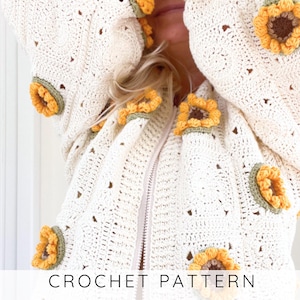 Könnte beinhalten: Cremefarbene Häkeljacke mit Reißverschluss und Sonnenblumen-Applikationen. Die Sonnenblumen sind gelb und braun mit grünen Akzenten. Die Jacke hat eine Kapuze und ist mit den Worten "CROCHET PATTERN" verziert.