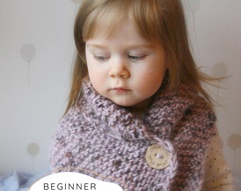 May include: A chunky knit cowl in a variegated dusty pink and grey yarn, featuring a large round wooden button closure. The text "BEGINNER KNITTING PATTERN" is printed in black at the bottom of the image over a white rounded shape.