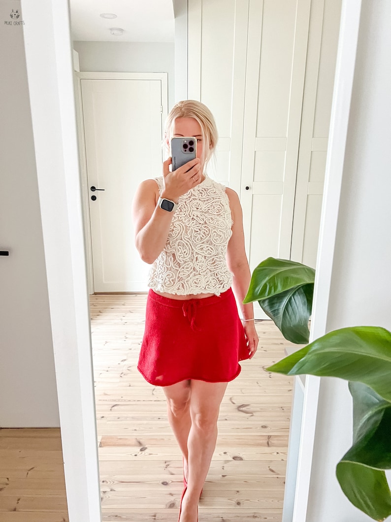May include: A cream-colored, sleeveless lace top paired with a bright red mini skirt. The skirt has a drawstring waist. The outfit is completed with red heels. The image is taken in front of a mirror.