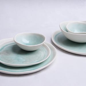 Conjunto de jantar com pratos e tigelas de porcelana turquesa, estilo minimalista natural, feito à mão.