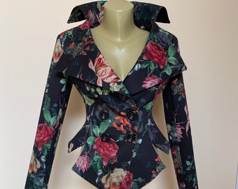 May include: A black blazer with a floral print featuring red, pink, and white roses. The blazer has a wide collar, a double-breasted closure, and a fitted silhouette.