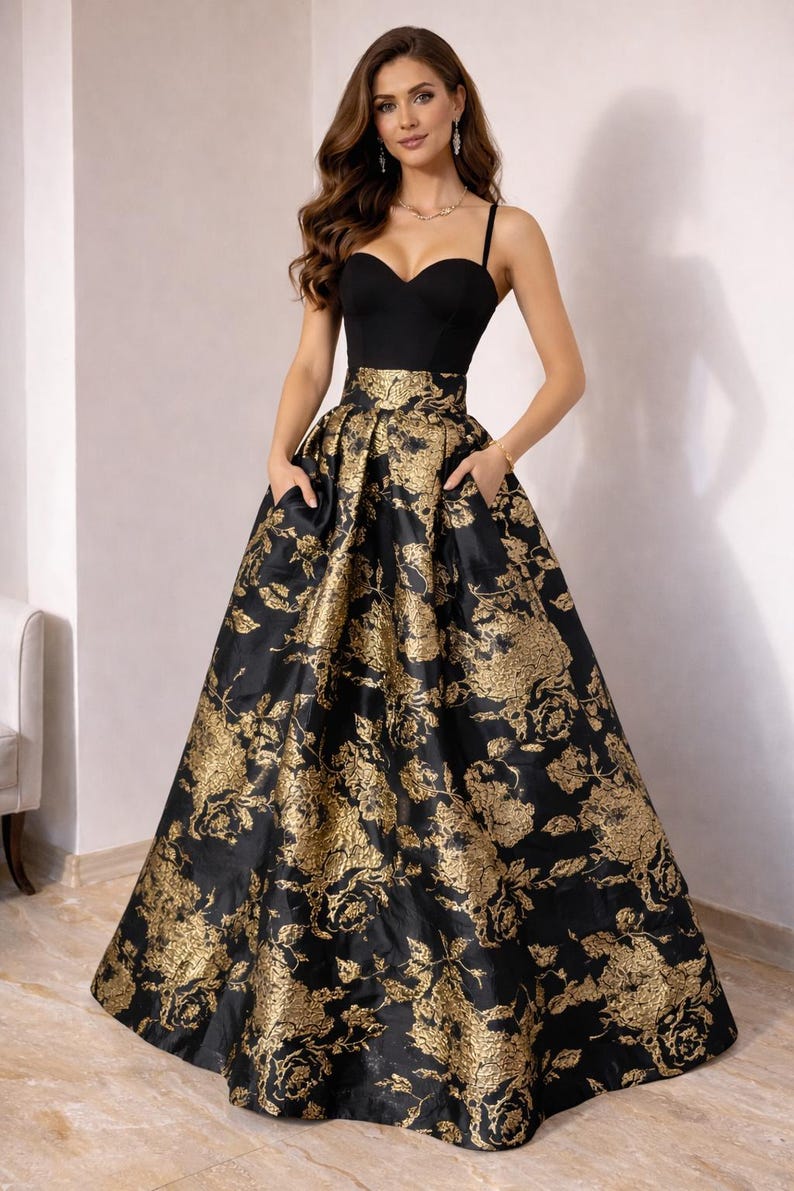 May include: A formal black gown with a sweetheart neckline and spaghetti straps. The full skirt features a gold floral brocade pattern. The dress has pockets and is suitable for special occasions.