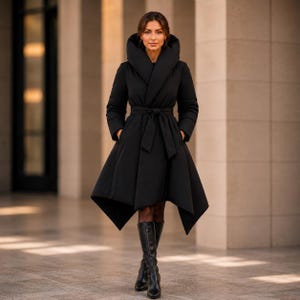 Può includere: Un cappotto imbottito nero con un ampio cappuccio, maniche lunghe e una cintura in vita. Il cappotto presenta un orlo asimmetrico che scende sotto le ginocchia, creando una silhouette svasata. È abbinato a stivali neri alti fino al ginocchio.