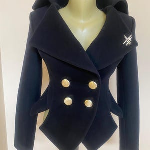 May include: A navy blue double-breasted jacket with gold buttons and a unique collar design. The jacket features a silver brooch and a tailored fit, showcasing a stylish and elegant aesthetic.