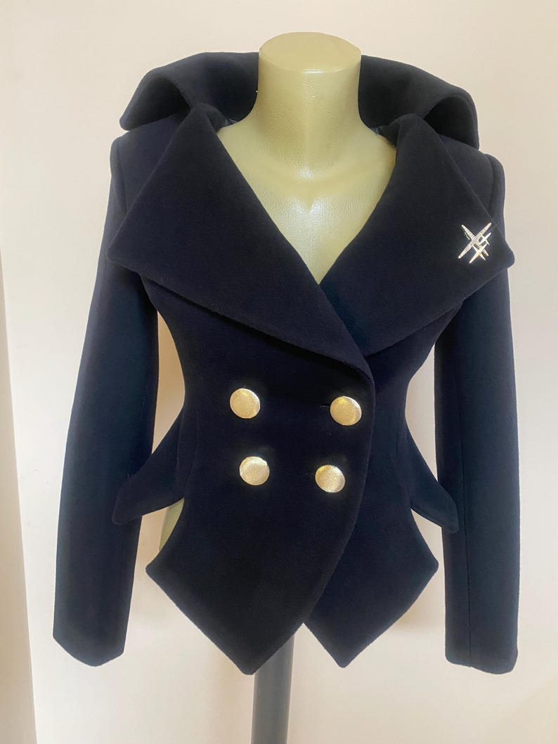 May include: A navy blue double-breasted jacket with gold buttons and a unique collar design. The jacket features a silver brooch and a tailored fit, showcasing a stylish and elegant aesthetic.