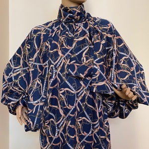 May include: A navy blue blouse with a high neck and long sleeves. The blouse has a pattern of gold chains and brown belts.