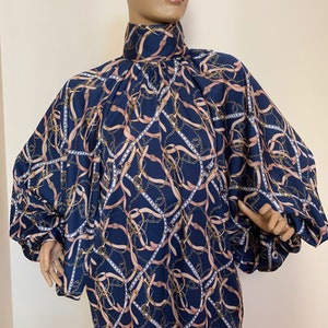 May include: A navy blue blouse with a high neck and long sleeves. The blouse has a pattern of gold chains and pink ribbons.