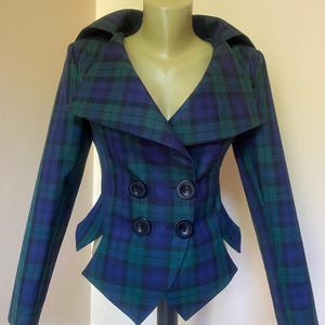 Peut inclure: Veste croisée à carreaux bleus et verts. La veste présente un large col, quatre boutons noirs et une coupe unique à la taille. La veste est présentée sur un mannequin.