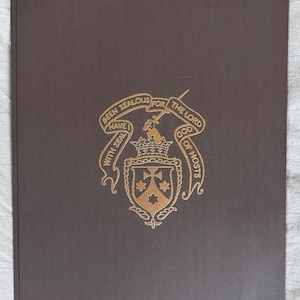 May include: A dark brown book cover with gold embossed text and a crest. The crest features a crown, shield, and banner with the words "Been Zealous For The Lord God of Hosts" and "With Zeal I Have".