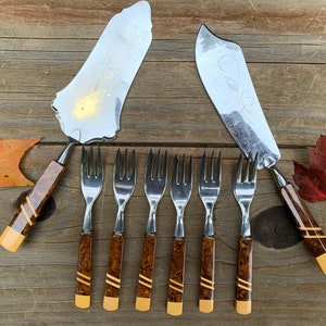 Pode incluir: Conjunto de garfos e servidores de bolo vintage com alças marmoreadas castanhas e amarelas. Os garfos têm um design simples e os servidores têm um padrão floral decorativo.