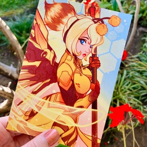 May include: A yellow and orange illustration of a character with a bee-themed costume and wings. The character is holding a staff with a yellow pom-pom on top. The background is a light blue with a honeycomb pattern.