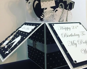 May include: A black and white 3D pop-up card with a silver glitter finish. The card is open to reveal a message that reads "Happy 21st Birthday To My Perfect Wife".