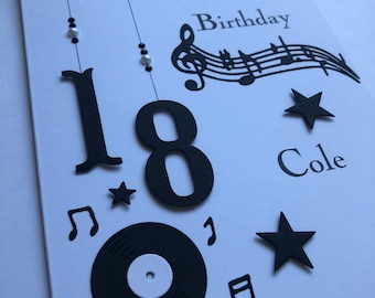 Könnte beinhalten: Eine weiße Karte mit schwarzen Noten, einer schwarzen Schallplatte und schwarzen Sternen. Die Karte sagt "Happy 18th Birthday Cole".