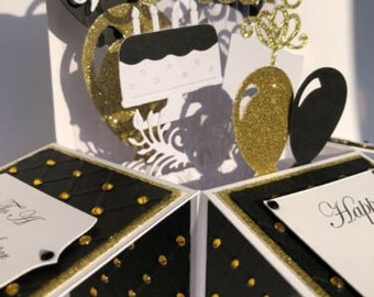 May include: A handmade black and gold pop-up card with the word "Music" in gold glitter. The card features a cake, hearts, and decorative elements. The card is open, revealing the interior design.