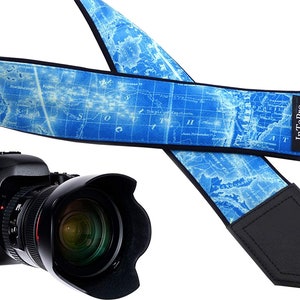 May include: A blue camera strap with a vintage world map design and black leather accents. The strap has the text "InTePro" printed on it.