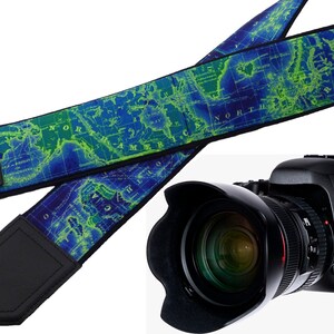 May include: A blue and green camera strap with a world map design. The strap has black leather padding and the text "IntePro" is printed on the strap. A black DSLR camera with a lens is also pictured.