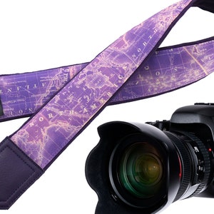 May include: Purple camera strap with a vintage world map design. The strap has a leather pad and the text "IntePro" is printed on the strap. A black DSLR camera with a lens is also in the image.