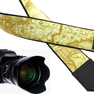 May include: A camera strap with a vintage world map design. The strap is made of a beige fabric with brown map details and has black leather ends with the brand name "InTePro" printed on one end.