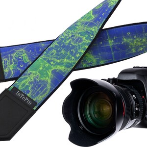 May include: A blue and green camera strap with a world map design. The strap has black padding and the text "IntePro" printed on it. The strap is attached to a black DSLR camera with a lens.