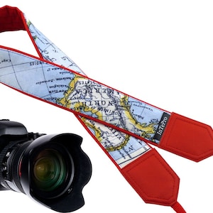 May include: Red camera strap with a map of North America printed on it. The strap has a red padded section and a black label that says "InTePro".