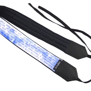 May include: Black camera strap with a blue and white printed quote that reads "Success is falling nine times and getting up ten. Happiness is an attitude. He either makes us stumble or he helps us to rise. If you want light to come into your life, you need to open your heart to the sun. All you can change is yourself, but sometimes that changes the whole world. Hope is a waking dream." The strap has a black leather end with the brand name "InTePro" printed on it.