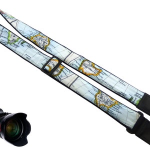 May include: A camera strap with a world map design. The strap is black with a blue and white world map printed on it. The strap has a black adjustable buckle.
