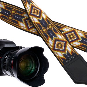 May include: A black camera with a lens and a black and yellow patterned camera strap with the text "InTePro" on the strap.