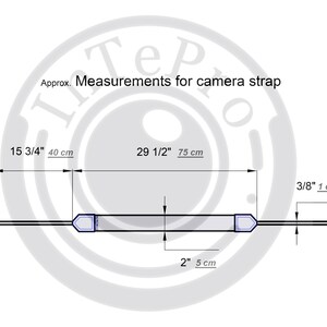 May include: Diagram showing the measurements of a camera strap. The strap is 15 3/4 inches (40 cm) long and 2 inches (5 cm) wide. The strap has two adjustable ends, each measuring 3/8 inch (1 cm) wide.
