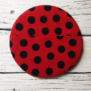 May include: Red fabric circle with black polka dots. The fabric is sewn together to create a pocket.