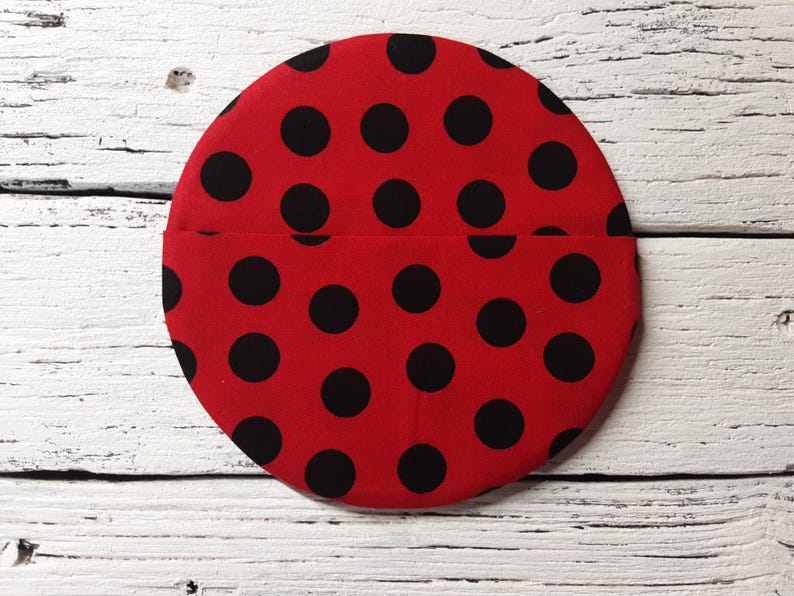 May include: Red fabric circle with black polka dots. The fabric is sewn together to create a pocket.