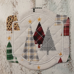 May include: A white quilted pot holder with a scalloped edge features a design of three Christmas trees in different plaid patterns. The trees are surrounded by gold stars.