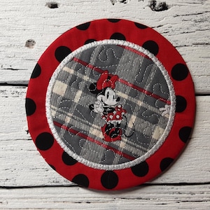 May include: Red and black polka dot fabric coaster with a white and gray plaid fabric center featuring a cartoon image of Minnie Mouse.