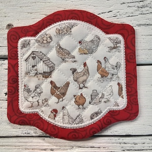 May include: Red and white quilted pot holder with a farmhouse theme featuring chickens, a coop, and eggs.