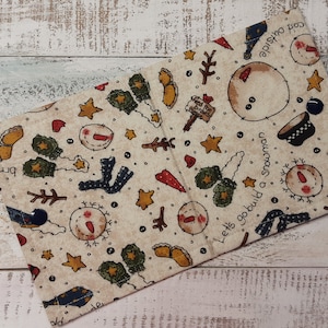 May include: Beige fabric with a repeating pattern of snowmen, stars, and winter-themed illustrations. The text "Let's go build a snowman" and "Cold outside" are printed on the fabric.