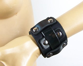 May include: Black leather bracelet with silver studs and a textured design.
