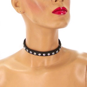 May include: A black choker necklace with clear rhinestones. The necklace is made of faux leather and has a simple, elegant design.