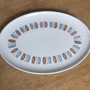 May include: White oval serving platter with a brown and blue geometric pattern around the edge.