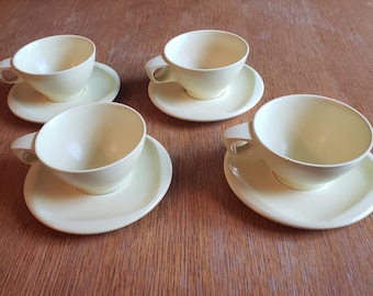 May include: Set of four pale yellow ceramic teacups and saucers. The cups and saucers are a simple, elegant design.