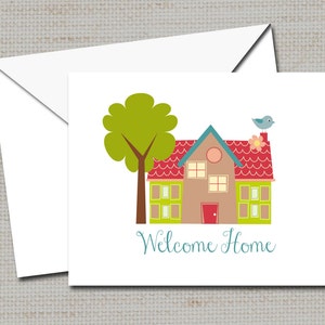 Puede incluir: Una tarjeta blanca con una ilustración colorida de una casa con un techo rojo, ventanas verdes y un pájaro azul en la parte superior. El texto "Welcome Home" está escrito en letras cursivas azules debajo de la casa.