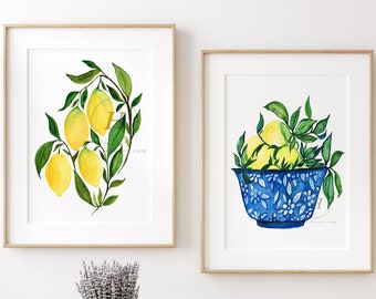 Könnte beinhalten: Zwei gerahmte Aquarellbilder von Zitronen. Das erste Bild zeigt einen Zitronenzweig mit grünen Blättern. Das zweite Bild zeigt eine blaue und weiße Schüssel gefüllt mit Zitronen und grünen Blättern.
