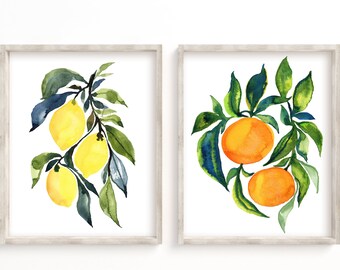 Könnte beinhalten: Zwei gerahmte Aquarellbilder von Zitruszweigen. Das linke Bild zeigt einen Zweig mit Zitronen und grünen Blättern. Das rechte Bild zeigt einen Zweig mit Orangen und grünen Blättern.