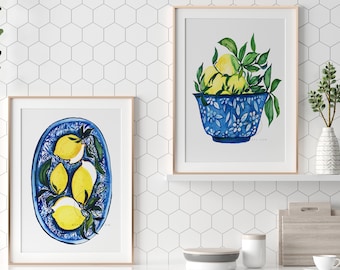 Könnte beinhalten: Zwei gerahmte Aquarellbilder von Zitronen in blauen und weißen Schalen. Das obere Bild zeigt eine Schale, die mit Zitronen und grünen Blättern überquillt. Das untere Bild zeigt einen Teller mit Zitronen.