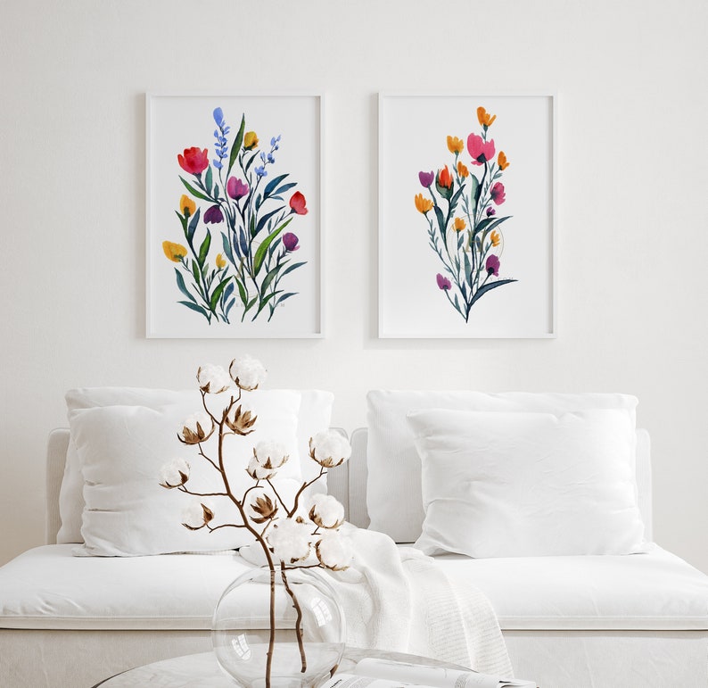 May include: Two framed watercolour paintings of floral bouquets. The paintings are in a minimalist style with white backgrounds and feature colourful flowers in shades of pink, red, orange, yellow, and blue.