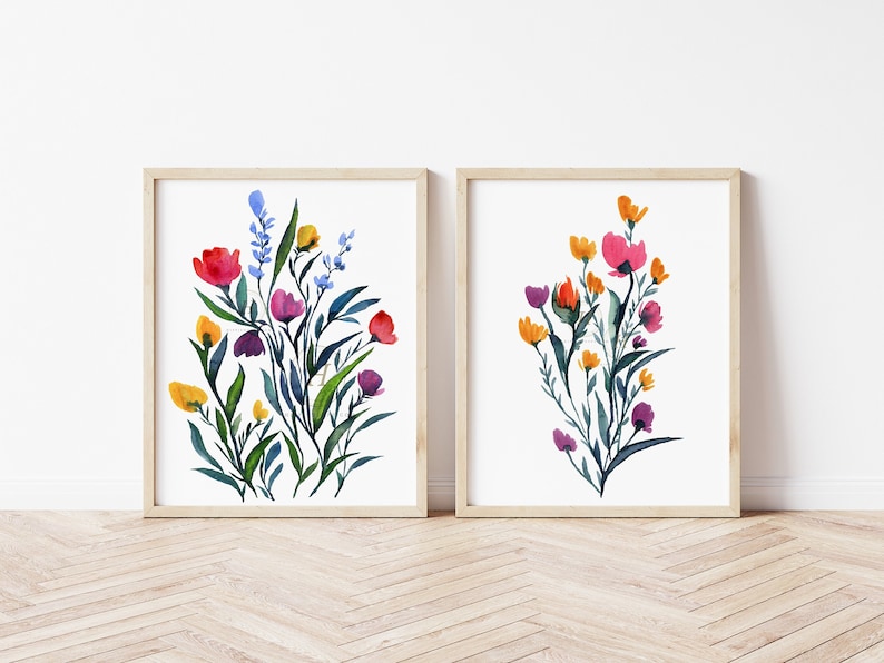 May include: Two framed watercolour paintings of colourful flower bouquets. The first painting features a bouquet of pink, red, yellow, blue, and purple flowers. The second painting features a bouquet of orange, pink, yellow, and purple flowers.