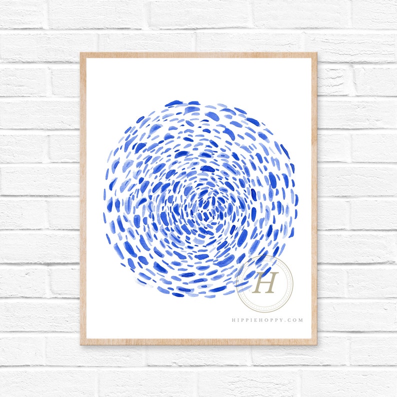 May include: A blue and white abstract watercolor print with a circular design of small blue dots. The print is framed in a light wood frame.