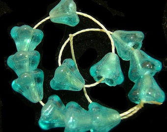 May include: A strand of teal blue glass beads in the shape of bells. The beads are strung on a white thread.